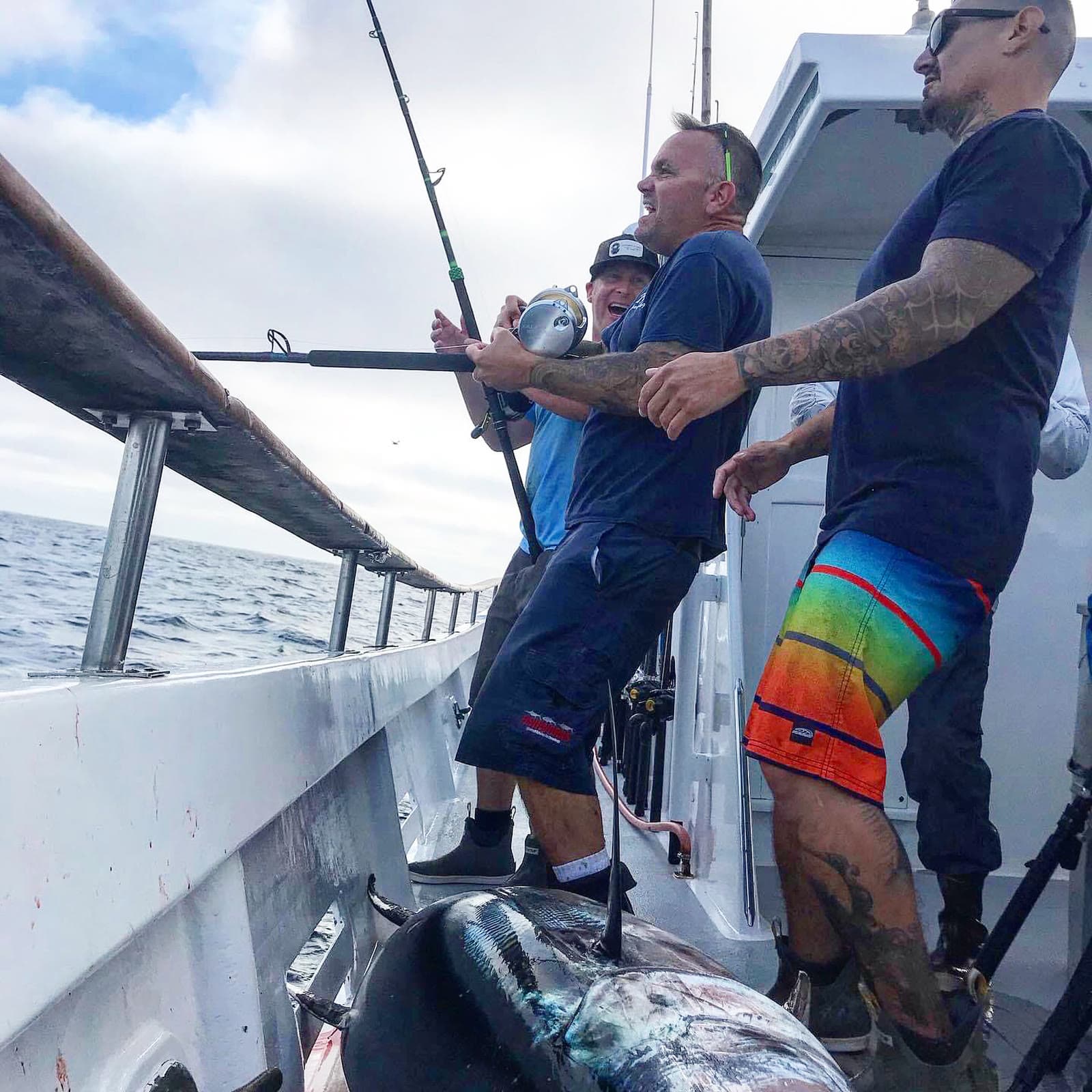 Anglers fighting a tuna with the catch already on deck